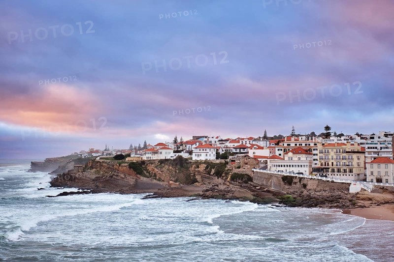 Beautiful sunset at Praia das Macas beach in Portugal. The village overlooks the ocean with colorful skies, creating a picturesque scene of natural beauty and serenity