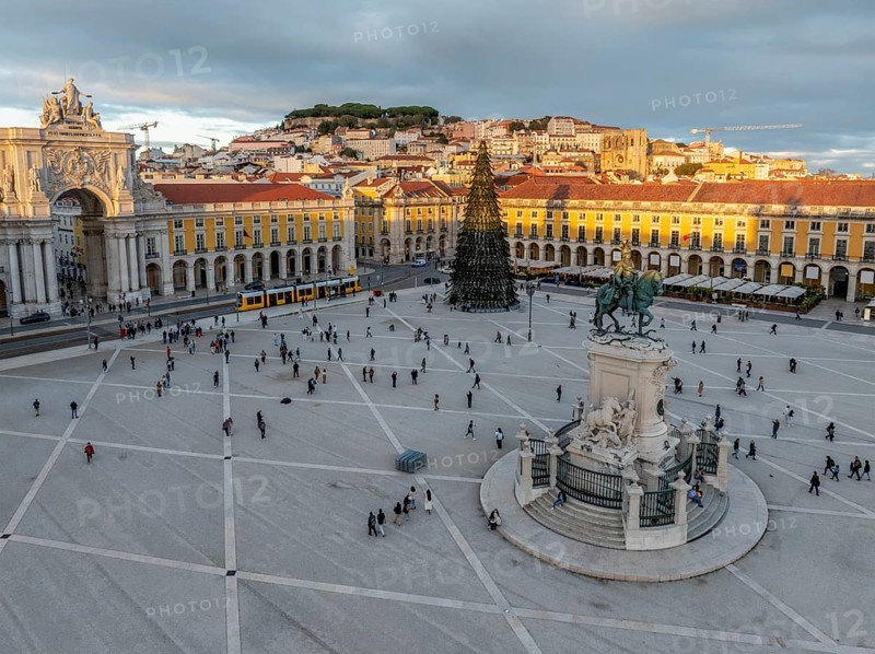 The scenic Praca do Comercio in Lisbon showcases a Christmas tree against the sunset sky, highlighting festive winter charm in the evening. Lisbon, Portugal