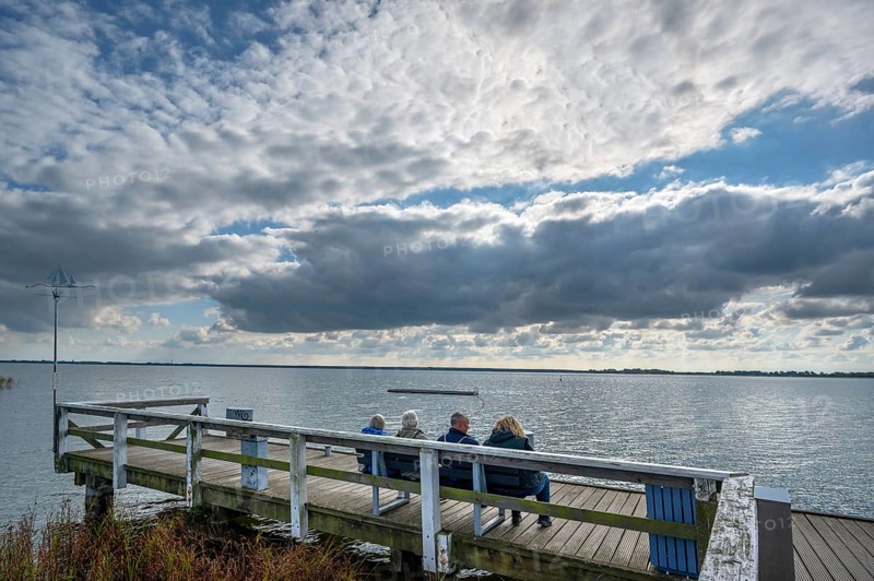 Tourists sitting on a bench at Wustrow harbour, DarÃŸ, Mecklenburg-Western Pomerania, Germany