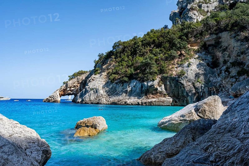 Light blue clear sea on a dream beach on Cala GoloritzÃ©, picturesque rocky coast, cliffs with rock arch, Golfo di Orosei, Baunei, Sardinia, Italy
