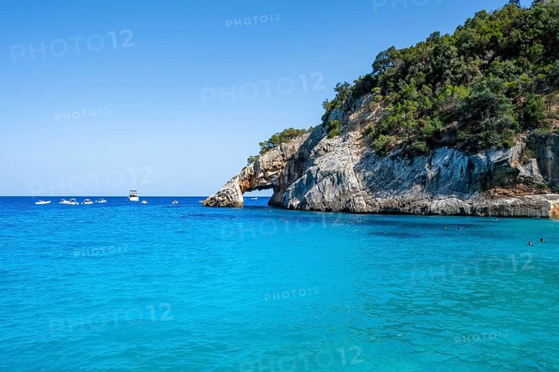 Light blue clear sea on a dream beach on Cala GoloritzÃ©, picturesque rocky coast with rock tunnel, cliffs, Golfo di Orosei, Baunei, Sardinia, Italy