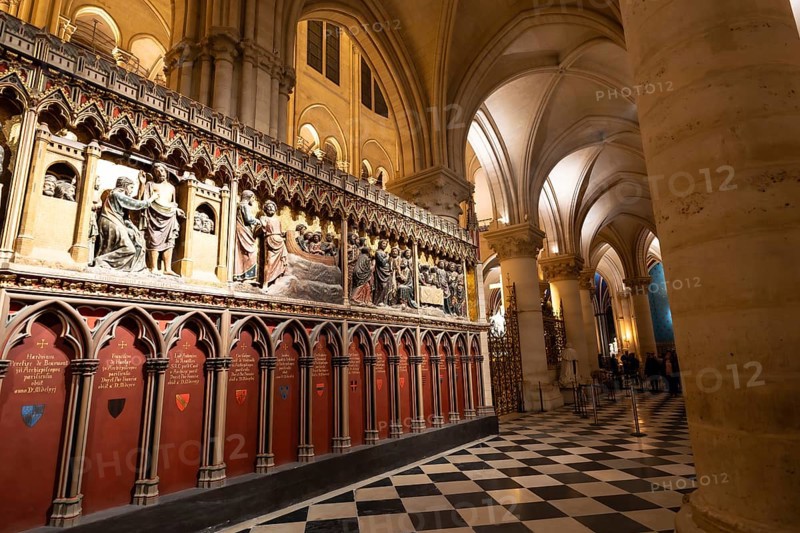 Notre dame cathedral interior with ornate gothic choir screen of detailed biblical sculptures, checkered marble floor and soaring arched columns in historic paris landmark
