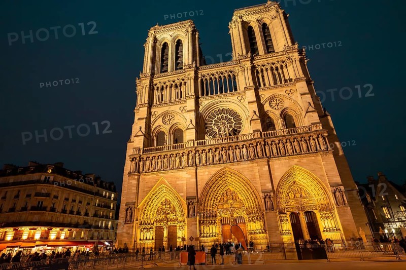 Notre dame de paris cathedral standing illuminated against the dark night sky, showcasing its stunning gothic architecture and intricate facade details