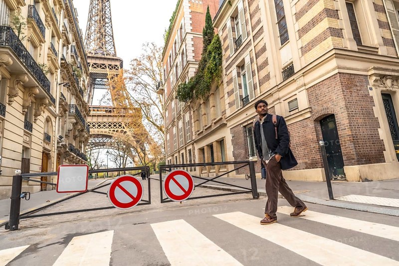 Young man crossing a street in paris, walking towards the iconic eiffel tower, embodying city travel, urban adventure, and exploring european landmarks