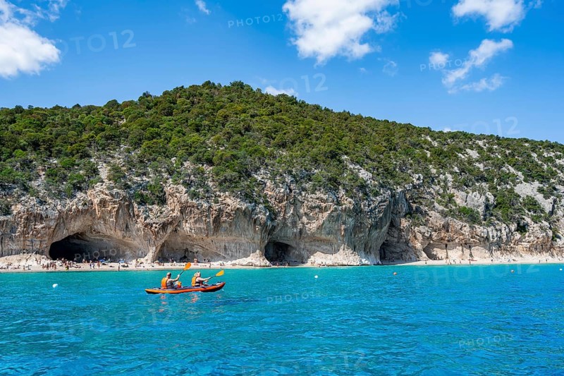 Kayakers in clear blue water, picturesque rocky coast, cliffs and Cala Luna beach, Golfo di Orosei, Baunei, Sardinia, Italy