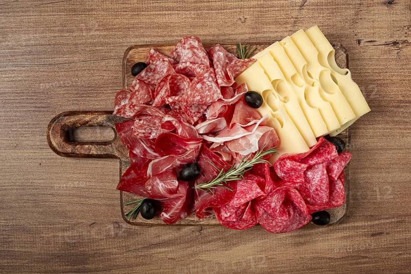Assorted meat, appetizer, prosciutto, salami and ham, with maasdam cheese and olives, on a wooden board, breakfast, top view, close-up, no people