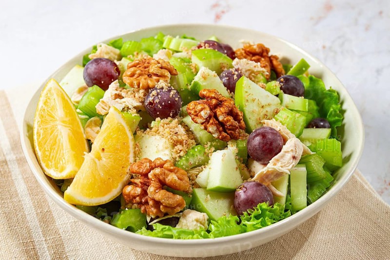 Fresh Waldorf salad, celery stalk with chicken, apple and walnuts, grapes, herbs, homemade, without people