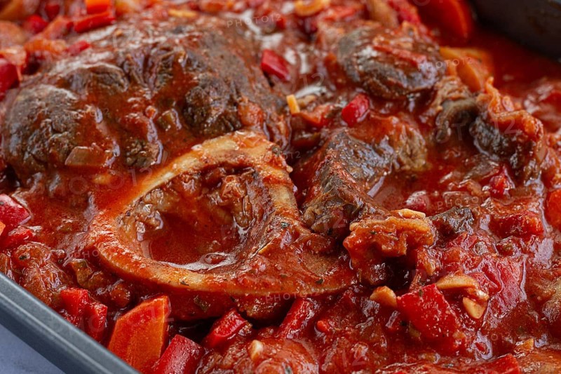 Ossobuco stew with vegetables, knuckle on the bone with new potatoes, in tomato sauce, homemade, top view, no people
