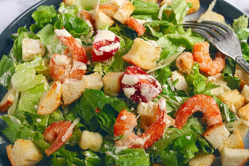 Caesar salad, with shrimp, on a marble background, top view, no people