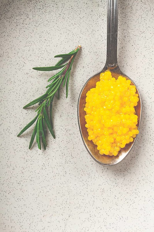 Yuzu caviar is pearly, on a spoon, top view, light background, no people