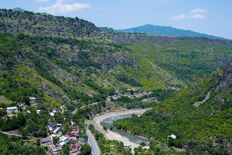A valley with a river surrounded by wooded mountains and scattered houses under blue skies, views of Sanahin, Debed River, Debed Gorge, Lorikeet Province, Armenia