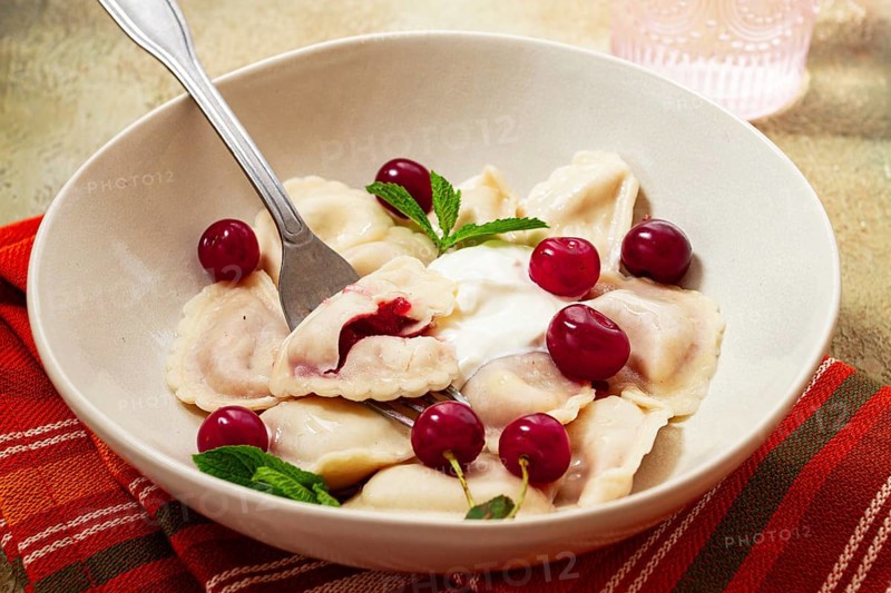 Traditional dumplings with cherries and yogurt, close-up, no people