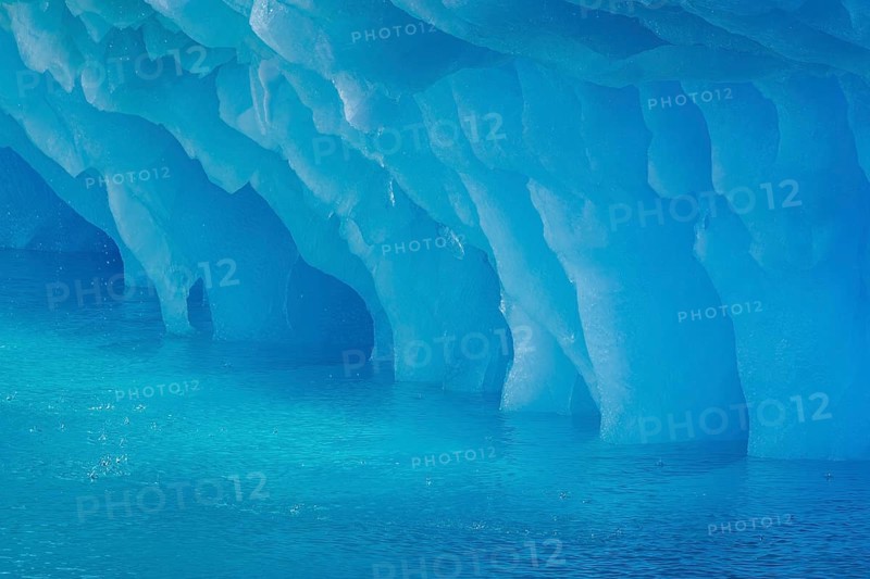 Dripping blue ice pattern from erosion by sea water on base of melting iceberg in the Arctic Ocean at Svalbard / Spitsbergen, Norway