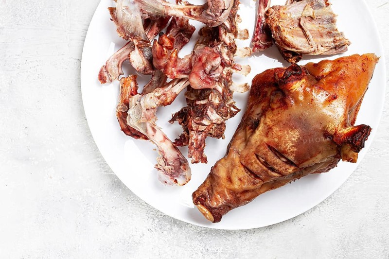 Roast pork head, with remnants of bones and meat, on a white platter, no people, close-up