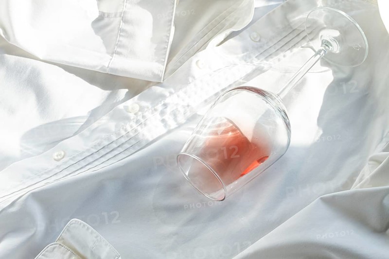 Glass, with pink wine, spilled on a white shirt, close-up, selective focus, no people, concept, top view