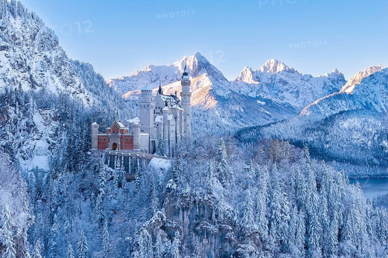 Wintery Neuschwanstein Castle in a snowy mountain landscape. Bright sun rays on the peaks, Schwangau near FÃ¼ssen, OstallgÃ¤u, AllgÃ¤u, Bavaria, Germany