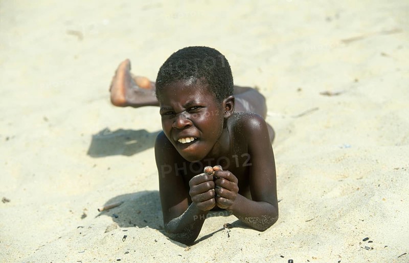 Local boy lying in the sand at Kande Beach on Lake Malawi and smiling at the camera, Malawi, Africa, July 2000, vintage, retro, old, historic