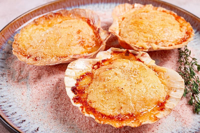 Scallop, baked in shells, with cheese and spices, on a plate, homemade