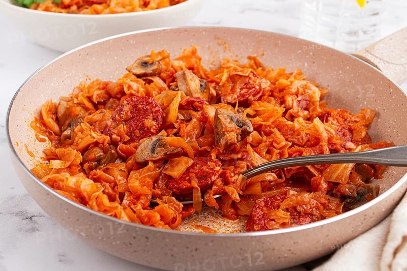 Bigos, Polish dish bigos, on the table, pan with stewed meat, with cabbage, chorizo sausages, mushrooms, homemade, without people