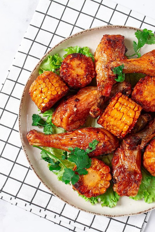 Fried chicken drumsticks, Mexican style, with corn, on a plate, close-up