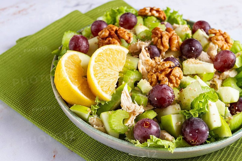 Fresh Waldorf salad, celery stalk with chicken, apple and walnuts, grapes, herbs, homemade, without people