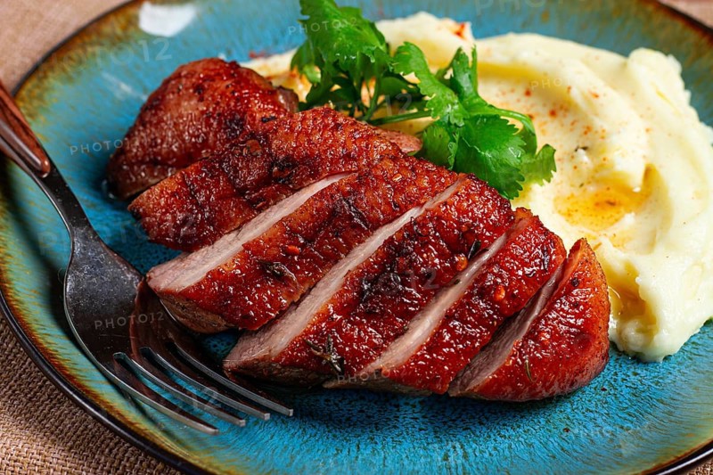 Roast duck breast, sliced with mashed potatoes, on a plate, close-up, no people