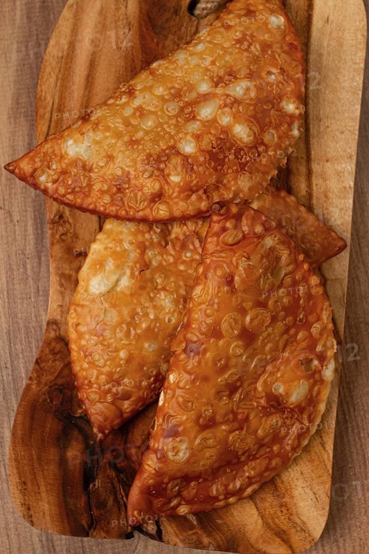 Fried chebureks, close-up, on a wooden chopping board, no people