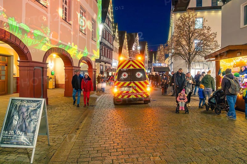 Busy Christmas market at night with rescue service vehicle and festive lighting, Christmas market 2025, Nagold, Black Forest, Calw district, Germany