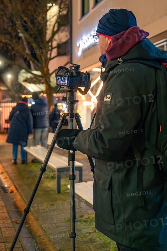 A photographer sets up his camera on the street at night, Christmas market 2025, Nagold, Black Forest, Calw district, Germany