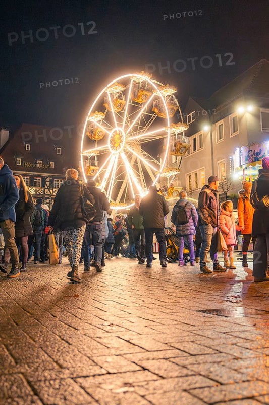 People walk across a square with illuminated Ferris wheel at night, Christmas market 2025, Nagold, Black Forest, Calw district, Germany