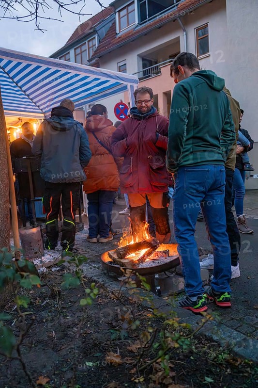 Small group of people around a warming campfire at a Christmas market on a cool evening, Aidlingen Christmas market, Böblingen district, Germany