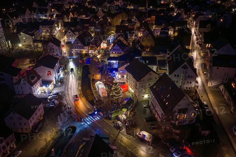 Night view of a Christmas market with glowing lights, roads and decorated Christmas tree, Aidlingen Christmas market, Böblingen district, Germany