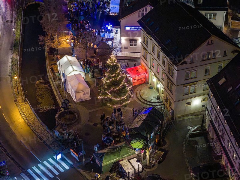 Market scene at night with Christmas tree, festive lights and people near tents, Aidlingen Christmas market, Böblingen district, Germany