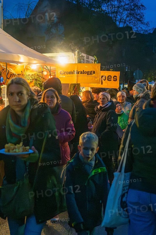 Crowd of people wait in front of an illuminated food stand at night, Aidlingen Christmas market, Böblingen district, Germany