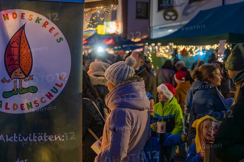 Visitors stroll through a brightly lit and festively decorated Christmas market with children, Aidlingen Christmas market, Böblingen district, Germany