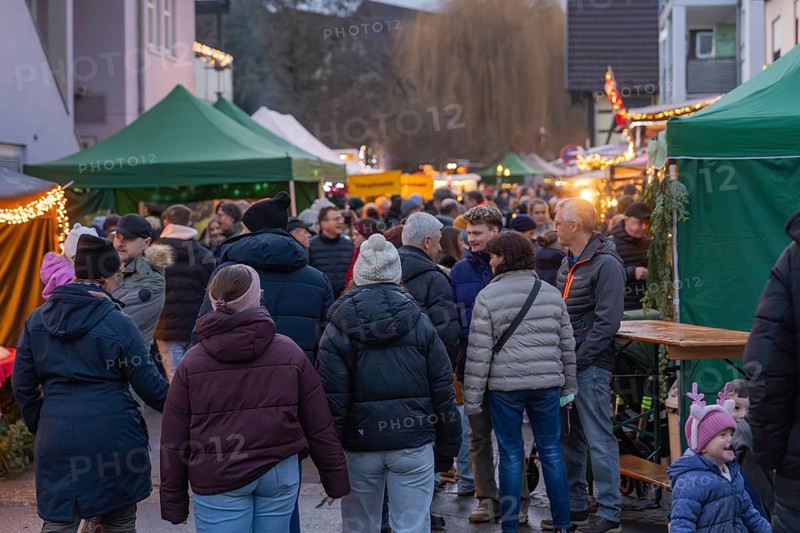 A crowd of people moves through a Christmas market with brightly decorated stalls, Aidlingen Christmas market, Böblingen district, Germany