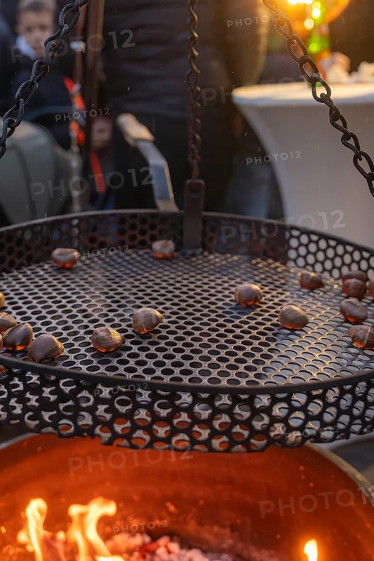 Roasting chestnuts over a fireplace at dusk, Aidlingen Christmas Market, Böblingen District, Germany