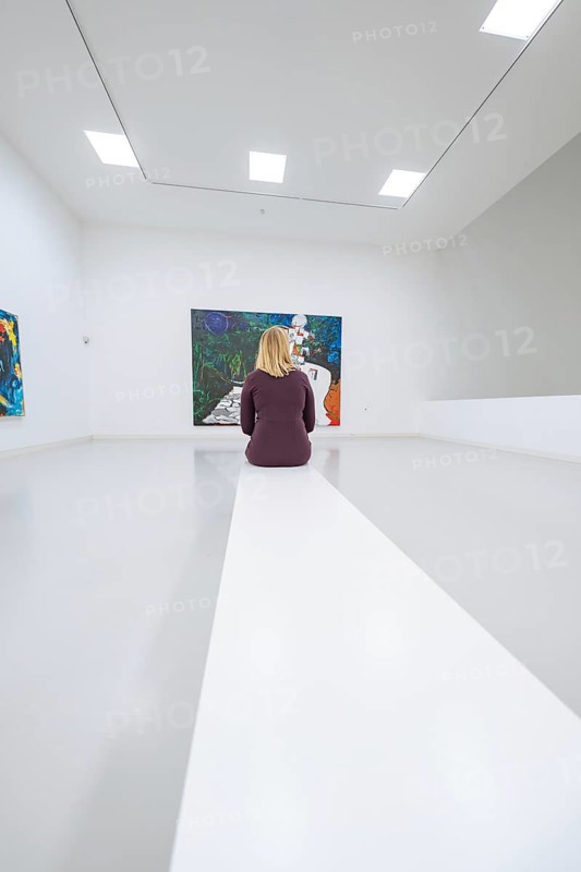 A woman sitting in a bright art gallery in front of an expressive painting, Open Horizons exhibition, Schauwerk Sindelfingen, BÃ¶blingen district, Germany