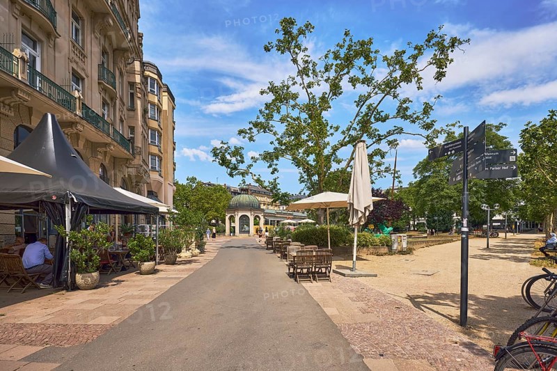 Square, historic building, residential building, outdoor area, restaurant palast-hotel, signpost, pavilion Kochbrunnen pavilion, footpath, park, trees, paths, pedestrians and visitors as a secondary motif, blue sky, cumulus clouds, cirrus clouds, Kochbrunnenplatz, Wiesbaden, state capital, district-free city, Hesse, Germany