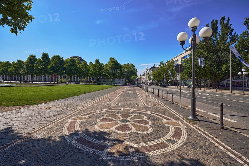 Paving stone sidewalk, mosaic, pattern, barrier bollard, lantern, trees, flags on flagpoles, general architecture, blue sky, cirrus clouds, WilhelmstraÃŸe street, Wiesbaden, state capital, district-free city, Hesse, Germany
