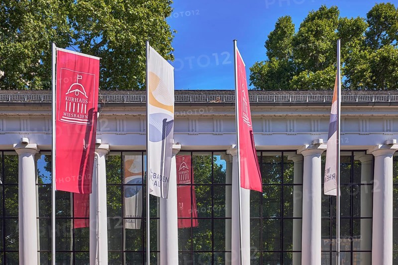 Spa hotel colonnades, colonnades, flags on flagpoles, spa hotel Wiesbaden, historic building, windows, pillars, trees, blue sky, cloudless, Kurhausplatz, Wiesbaden, state capital, district-free city, Hesse, Germany