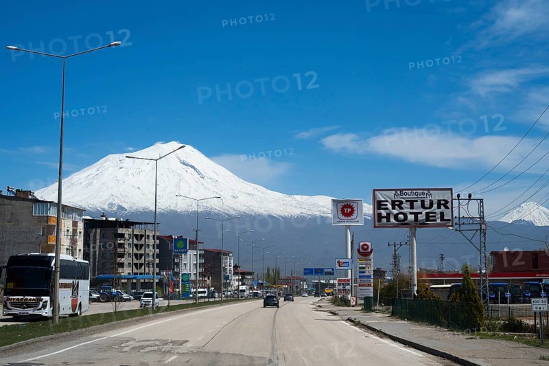 Road with passing vehicles flanked by a hotel and snow-capped mountains in the background, Great Ararat, BÃ¼yÃ¼k AÄŸrÄ± DaÄŸÄ±, Dogubayazit, DoÄŸubayazÄ±t, Dogubeyazit, Agri Province, Eastern Anatolia, Anatolia, Turkey