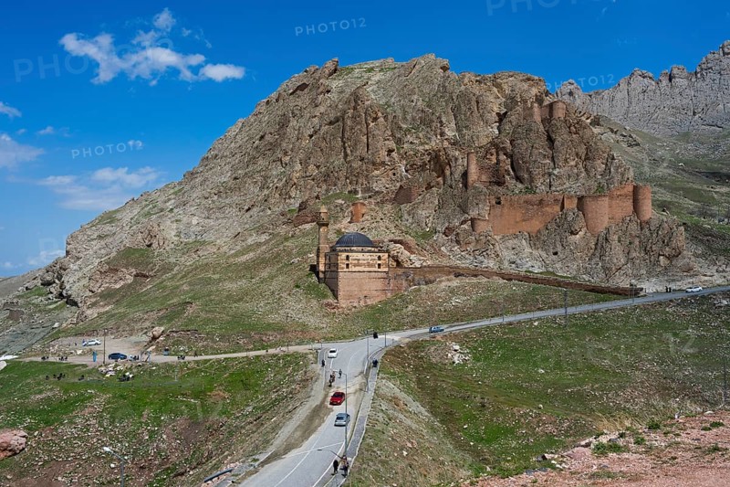 A fortress on a mountain with a road and cars in the foreground under a clear blue sky, Eski BayezÄ±d Cami, Old Bayezid Mosque and DoÄŸubayazÄ±t Castle, Dogubayazit, DoÄŸubayazÄ±t, Agri Province, AÄŸrÄ±, Eastern Anatolia, Anatolia, Turkey