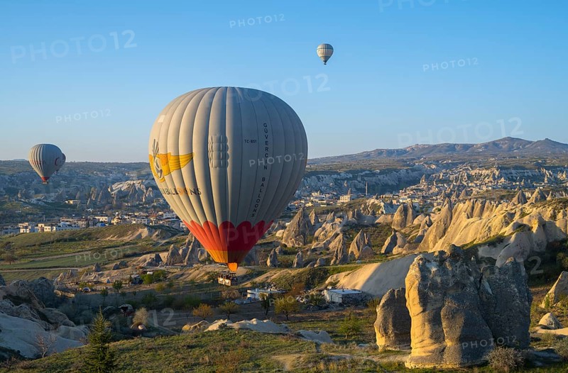 Hot air balloons float over a rocky landscape at sunrise in Capadocia, Göreme National Park, Göreme Tarihî Millî ParkÄ±, Nevsehir Province, Nevsehir, Cappadocia, Cappadocia, Central Anatolia, Turkey