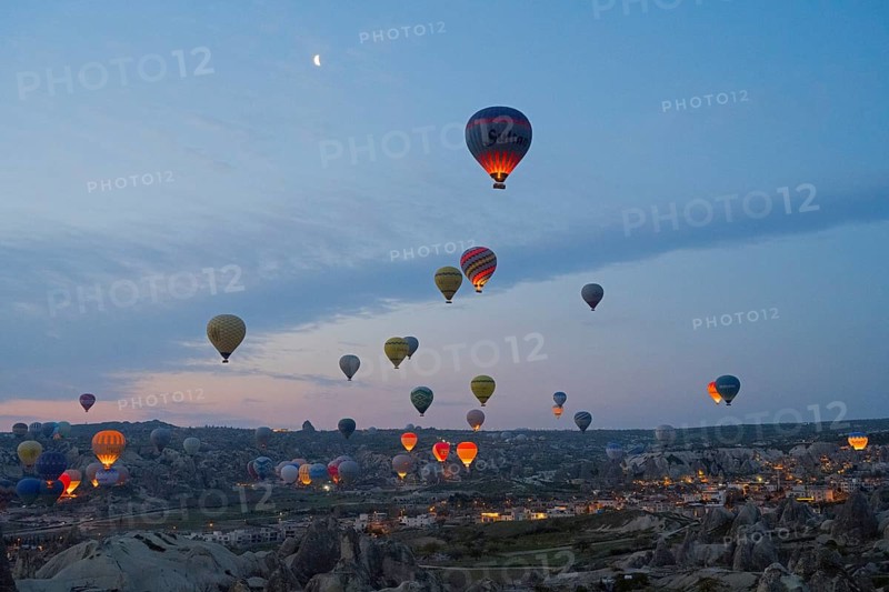 Many hot air balloons float at dusk over the picturesque landscape of Cappadocia, Göreme National Park, Göreme Tarihî Millî ParkÄ±, Nevsehir Province, NevÅŸehir, Cappadocia, Cappadocia, Central Anatolia, Turkey
