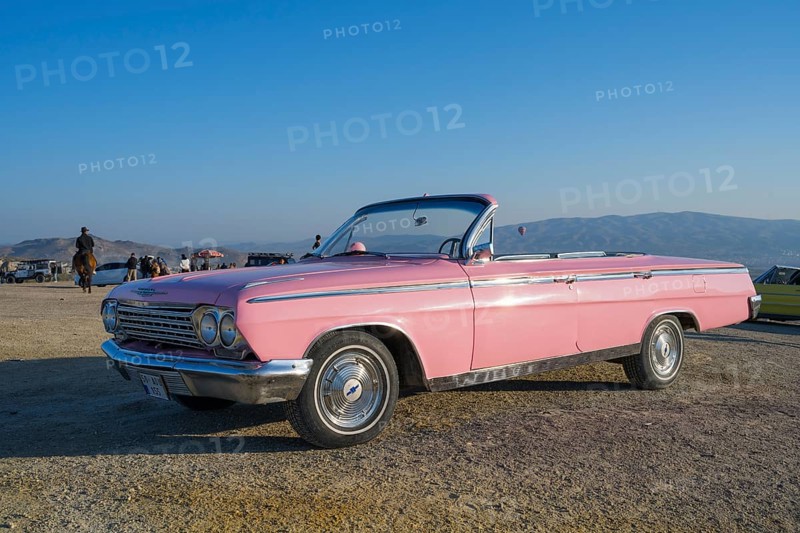 A pink vintage convertible car stands in a vast landscape with mountains in the background and blue sky, Chevrolet, Göreme National Park, Göreme Tarihî Millî ParkÄ±, Nevsehir Province, NevÅŸehir, Cappadocia, Cappadocia, Central Anatolia, Turkey