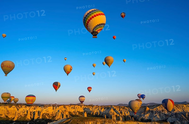 Hot air balloons float over rocks in a vast landscape in morning light, Göreme National Park, Göreme Tarihî Millî ParkÄ±, Nevsehir Province, Nevsehir, Cappadocia, Capadocia, Central Anatolia, Turkey