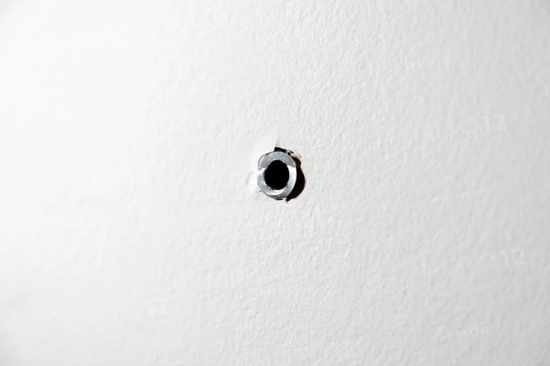 Single drill hole with dowel in a white wall