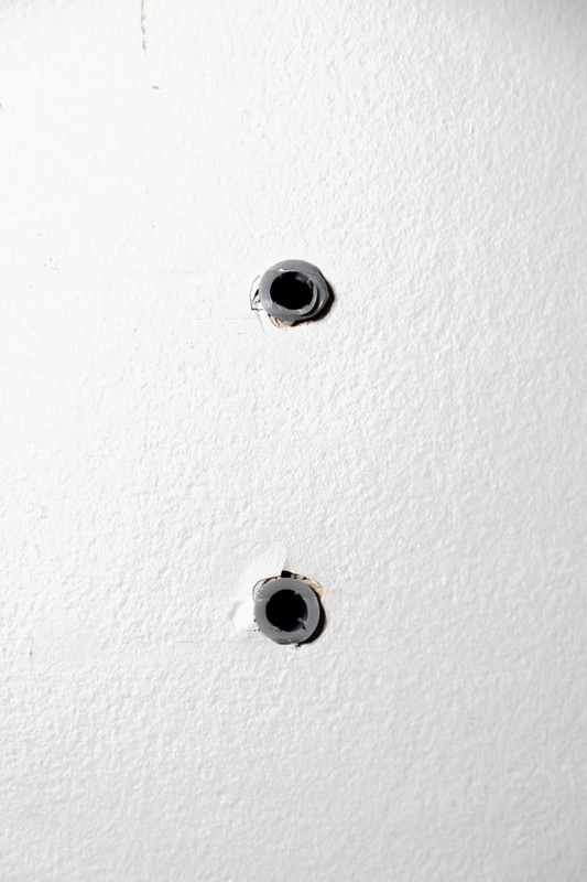Two drill holes with dowels in a white wall