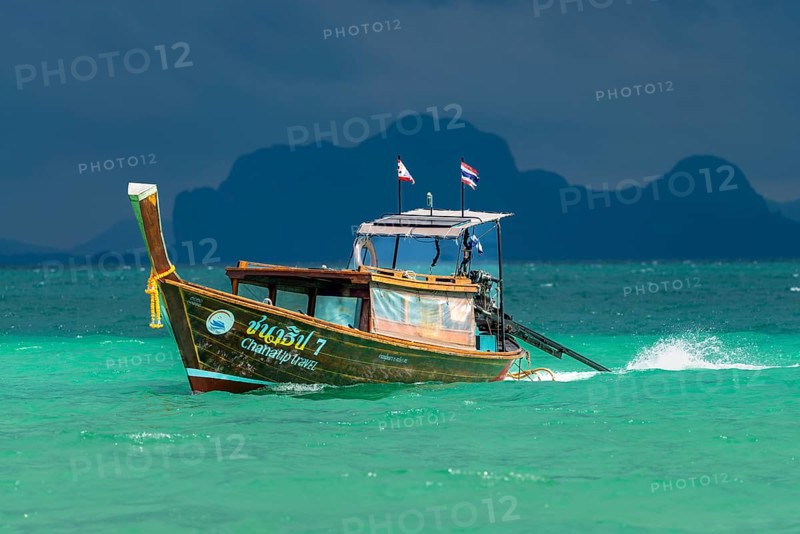 Longtail boat in fast drive to the beach, behind it an approaching thunderstorm, Koh Ngai island, Andaman Sea, Satun province, southern Thailand, Thailand